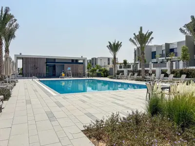 a swimming pool with chairs and trees and buildings at Frank Porter - La Rosa 6 in Dubai