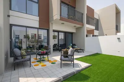 a patio with chairs and a table and grass at Frank Porter - La Rosa 6 in Dubai