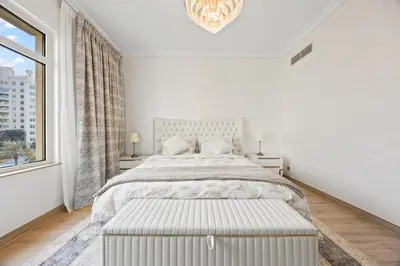 a white bedroom with a large bed and a window at 2BDR Luxury Apartment in Palm in Dubai