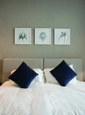 a bed with blue pillows and three pictures on the wall at Luxurious Studio in Heart of Business Bay in Dubai