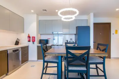 a kitchen with a wooden table and chairs at Forte, Downtown- Elegant 1-BR in Dubai