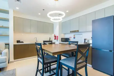 a kitchen and dining room with a wooden table and chairs at Forte, Downtown- Elegant 1-BR in Dubai