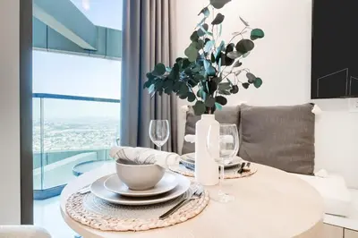 a dining room table with a vase of flowers on it at Cozy High-Floor Studio with Amazing Views in Dubai