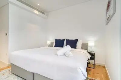 a bedroom with a large white bed with blue pillows at Shadow Of The Sun by Lagom in Dubai
