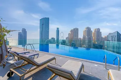a swimming pool with lounge chairs and a city skyline at Savis Homes - Condor Marina Star - Luxury 2 BR Waterfront Apartment in Dubai