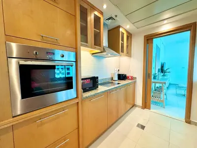 a kitchen with wooden cabinets and a stainless steel appliance at Amazing 1BR in Dubai Marina with Luxury Interiors in Dubai