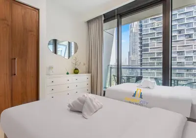 two white beds in a room with a window at Luxurious 2 Bed Next to Burj Khalifa, Hosted by Desert City Stays in Dubai