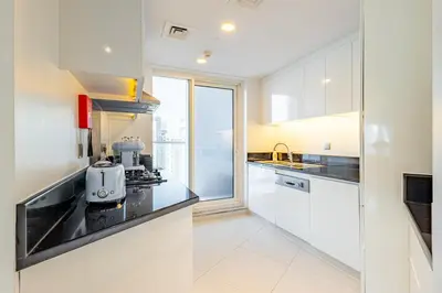 a kitchen with white cabinets and a large window at Deluxe One-Bedroom Apartment in Business Bay with Burj Khalifa and Canal View in Dubai