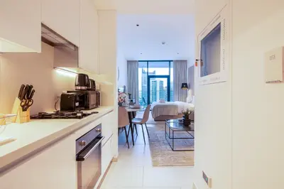 a kitchen with a stove and a living room at Marquise Square Studio, Business Bay in Dubai
