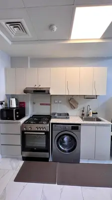 a kitchen with a stove and a washing machine at Millennium Binghatti Residence in Dubai