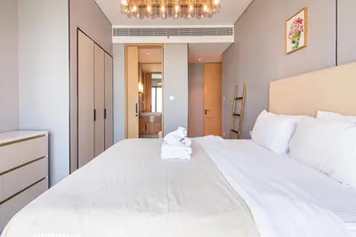 a bedroom with a large white bed with a chandelier at Address Residential 2 BDR, JBR in Dubai