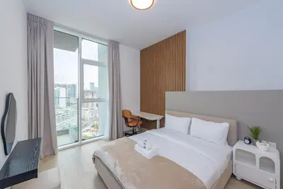 a hotel room with a bed and a large window at Bloom Heights 1 BR, JVC in Dubai