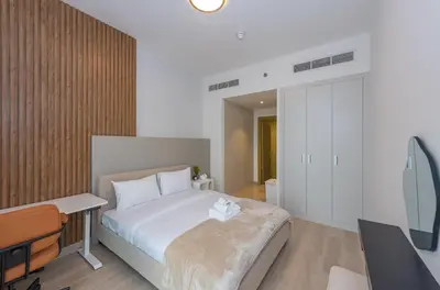 a bedroom with a large bed with a desk and a desk at Bloom Heights 1 BR, JVC in Dubai