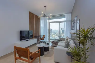 a living room with a couch and a tv at Bloom Heights 1 BR, JVC in Dubai