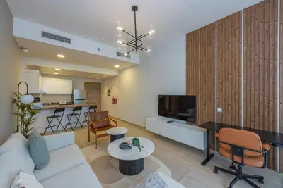 a living room with a white couch and a tv at Bloom Heights 1 BR, JVC in Dubai