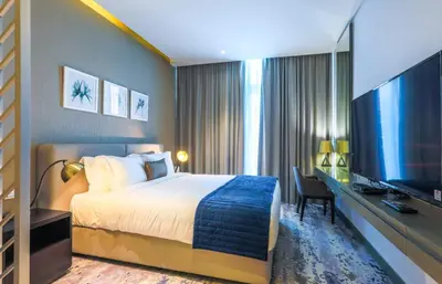 a hotel room with a bed and a flat screen tv at Damac Maison Prive, Business Bay- Gorgeous Studio in Dubai