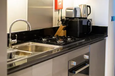 a kitchen with a sink and a stove and a microwave at Damac Maison Prive, Business Bay- Gorgeous Studio in Dubai