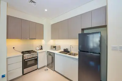 a kitchen with white cabinets and a black refrigerator at Park Heights 1 BR, Dubai Hills in Dubai