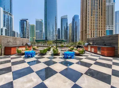 a checkered patio with tables and chairs and a city skyline at MBL Residences 1 BR, JLT in Dubai