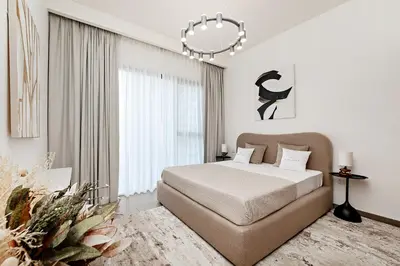 a white bedroom with a large bed and a chandelier at Premium Apartments at Executive Residences in Dubai