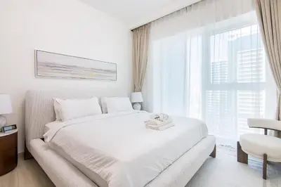 a white bedroom with a white bed and a window at Me Do Re1BR, JLT in Dubai