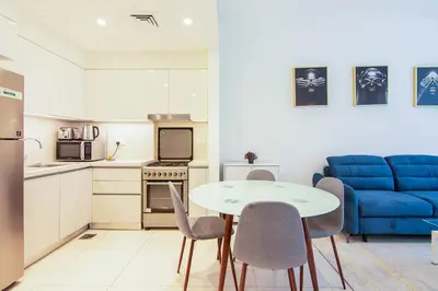 a kitchen with a table and chairs and a blue couch at Park Point 1 BR, Dubai Hills in Dubai