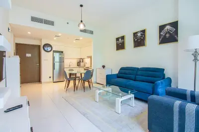 a living room with a blue couch and a table at Park Point 1 BR, Dubai Hills in Dubai