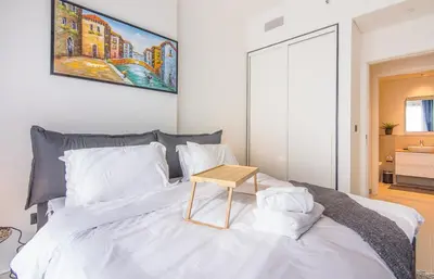 a bedroom with a white bed with a table on it at Collective 1,0 Dubai Hills- Cozy 1-BR in Dubai