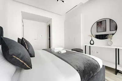 a white bedroom with a large bed with black pillows at StoneTree - Newly Furnished - Stylish in Dubai
