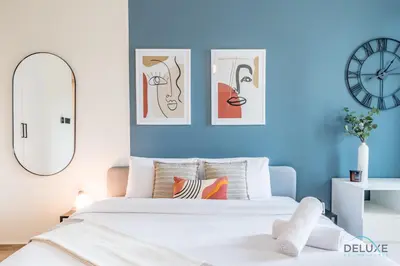 a bedroom with blue walls and a bed with four pictures at Exclusive Promo Luxe 1BR at a Special Price by Deluxe Holiday Homes in Dubai