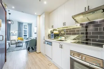 a kitchen with white cabinets and stainless steel appliances at Exclusive Promo Luxe 1BR at a Special Price by Deluxe Holiday Homes in Dubai