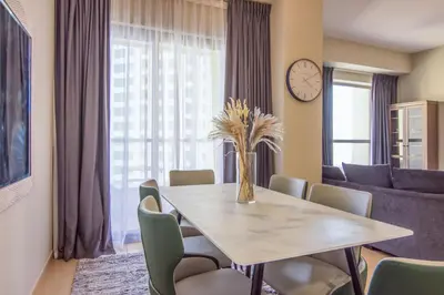 a dining room with a table and chairs and a clock at Two-Bedroom Apartment with Balcony in Shams 4, JBR in Dubai