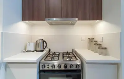 a white kitchen with a stove top oven at Park Heights, Dubai Hills- Cozy 1-BR in Dubai