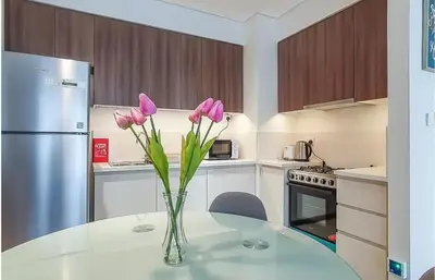 a vase of pink flowers sitting on a table in a kitchen at Park Heights, Dubai Hills- Cozy 1-BR in Dubai