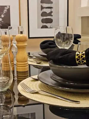 a table with plates and wine glasses on it at 1 Bedroom Apartment Paramount in Dubai