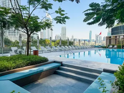 a swimming pool with lounge chairs and a city skyline at Luxurious 2BR The Address Opera in Dubai