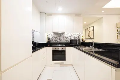 a white kitchen with a sink and a microwave at Panoramic Burj Khalifa views-64th floor infinity pool in Dubai
