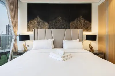 a bedroom with a large white bed with two lamps at Panoramic Burj Khalifa views-64th floor infinity pool in Dubai