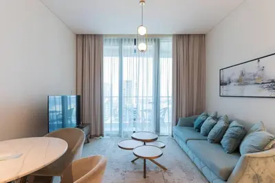 a living room with a blue couch and a table at Address JBR l Beachfront l Mid floor & opened view in Dubai