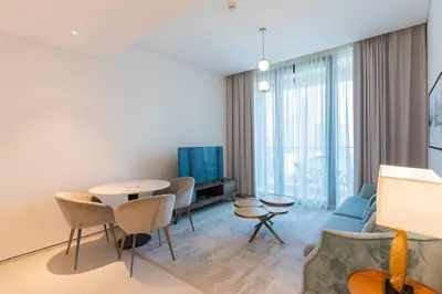 a living room with a table and a blue couch at Address JBR l Beachfront l Mid floor & opened view in Dubai