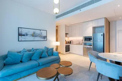 a living room with a blue couch and a table at Address JBR l Beachfront l Mid floor & opened view in Dubai