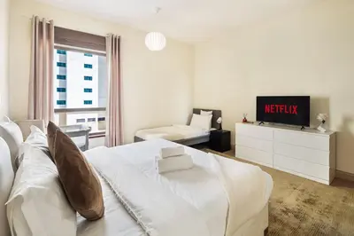 a white bedroom with a bed and a tv at Luxury 1 bedroom apartment in JBR with Beach access in Dubai