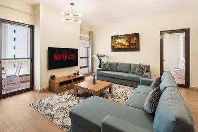 a living room with a couch and a tv at Luxury 1 bedroom apartment in JBR with Beach access in Dubai