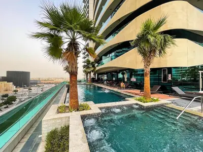 a swimming pool with palm trees in front of a building at Stylish Studio in Heart Downtown Next Dubai Mall in Dubai