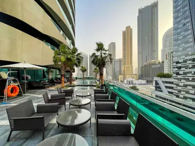a swimming pool with tables and chairs on a building at Stylish Studio in Heart Downtown Next Dubai Mall in Dubai