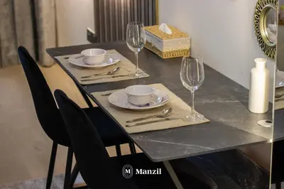 a dining table with glasses and plates and a candle at Manzil - Studio Apartment in Azizi Riviera near Dubai Mall in Dubai