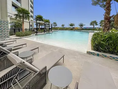 a swimming pool with tables and chairs next to a building at FIRST CLASS Studio Luxe Living in Dubai
