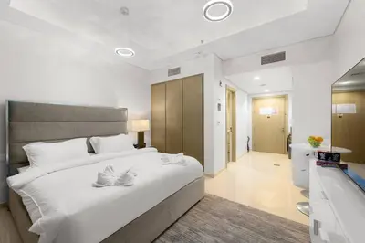 a bedroom with a large white bed and a bathroom at FIRST CLASS Studio Luxe Living in Dubai