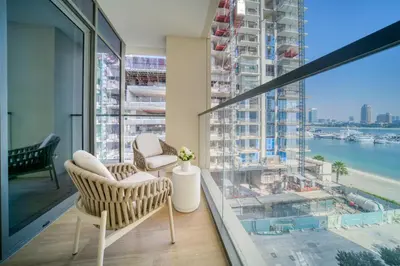 a balcony with two chairs and a view of the water at Luxury 2-Bed Apartment l Emaar Beachfront in Dubai
