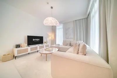 a white living room with a couch and a tv at Luxury 2-Bed Apartment l Emaar Beachfront in Dubai